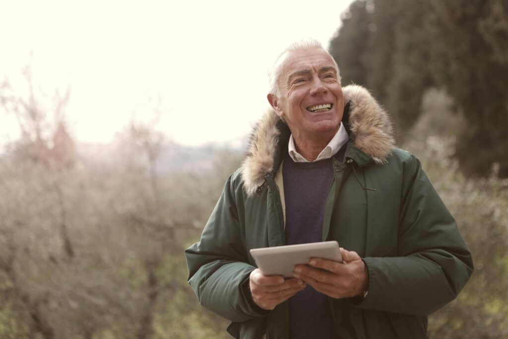 Man In Green Jacket Holding A Gadget